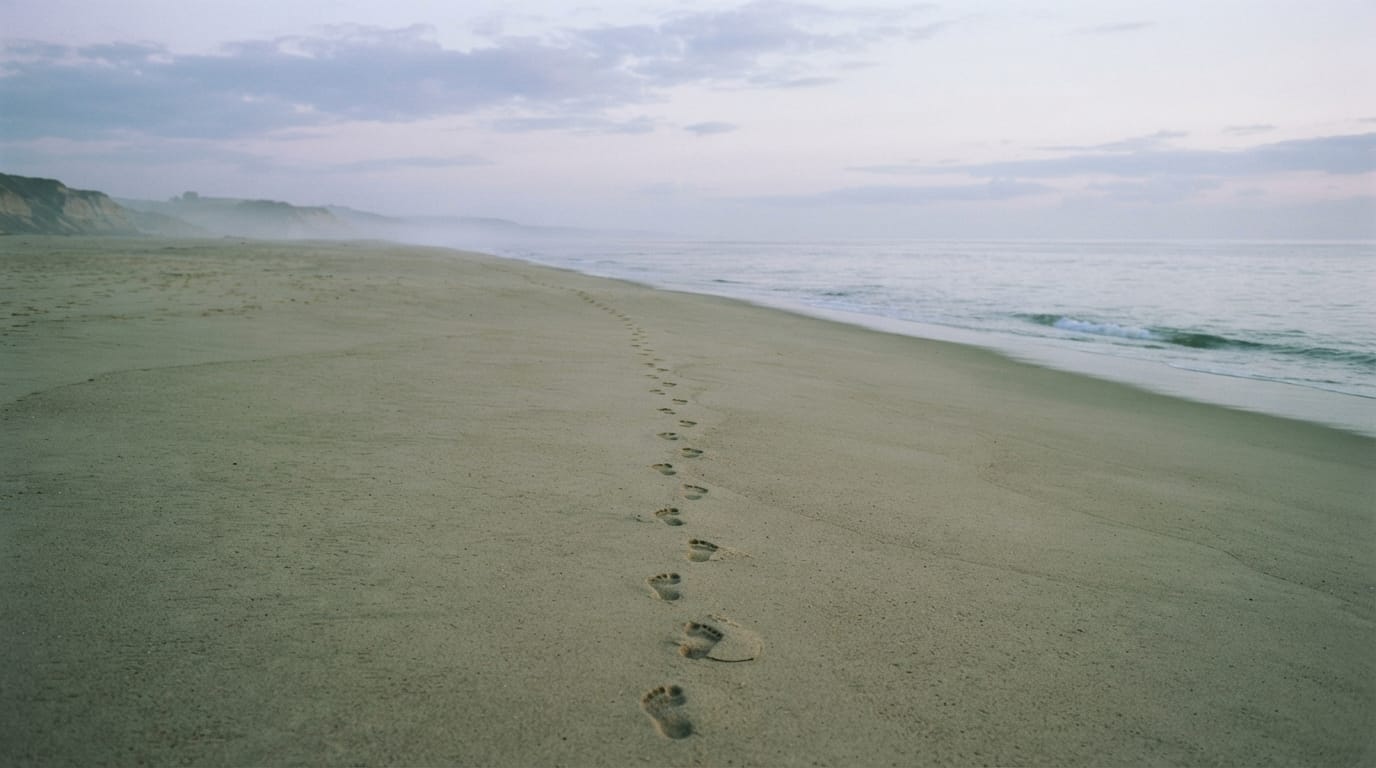A single line of footprints on an empty beach at dawn, disciplined and solitary, evoking Manhattan Beach